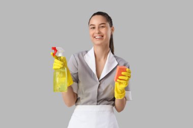 Temizlik süngeri ve hafif arka planda deterjanı olan genç oda hizmetçisi.