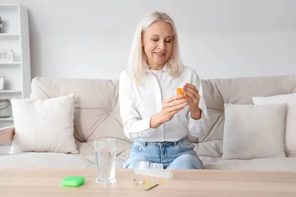 Mature woman taking pills in living room