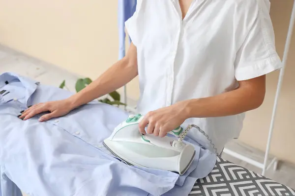 Woman ironing clothes in laundry room, closeup
