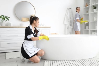 Genç oda hizmetçileri banyoyu temizliyor.