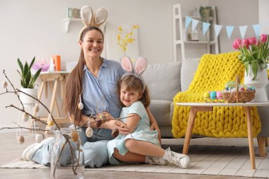 Genç anne ve küçük kızı tavşan kulağı takıp evde sarılıyorlar. Paskalya kutlaması