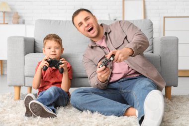 Mutlu baba ve küçük oğlu evde video oyunu oynuyorlar.