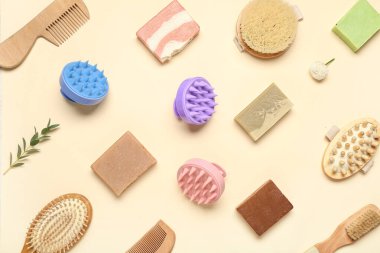 Saç derisi masaj aletleri, şampuan çubukları ve soluk sarı arka planda fırçalar.