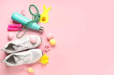 Spor malzemeleri, ayakkabılar ve pembe arka planda Paskalya dekoru olan kompozisyon