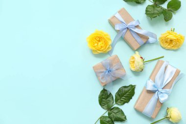 Cyan arka planda gül çiçekleriyle süslenmiş sevimli kağıt ambalajlı kompozisyon