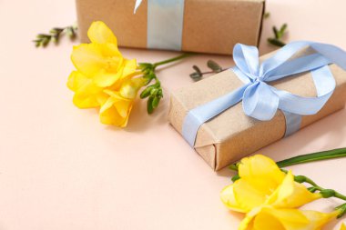 Bej arka planda doğal çiçeklerle süslenmiş şirin paketlenmiş hediye kutuları.