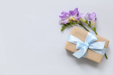 Hafif arka planda bahar çiçeği dekoru olan zarif paketlenmiş hediye kutusu.
