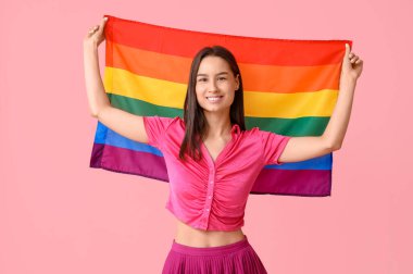 Pembe arka planda LGBT bayrağı olan mutlu genç bir kadın.