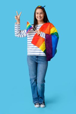 Mavi arka planda zafer jesti gösteren LGBT bayraklı güzel genç bir kadın.
