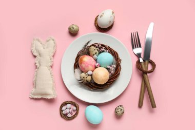 Paskalya yumurtaları ve pembe arka planda çigila çiçekleri olan güzel bir masa.