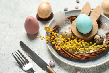 Paskalya yumurtaları ve beyaz arka planda tüyleri olan güzel bir masa.