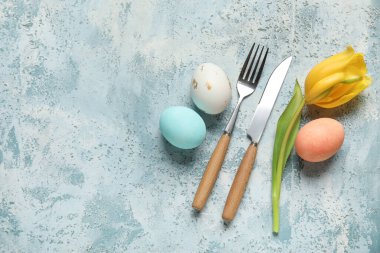 Paskalya yumurtaları ve açık mavi arka planda sarı laleli sofra takımı.
