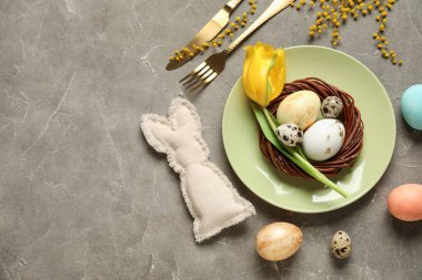 Paskalya yumurtaları ve gri arka planda sarı lale ile güzel bir masa.