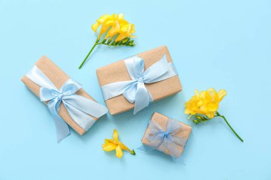 Şirin paketlenmiş hediye kutuları ve cyan arka planda çiçekler