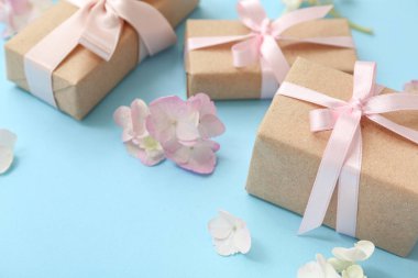 Şirin hediye kutuları ve cyan arka planda çiçekleri olan kompozisyon