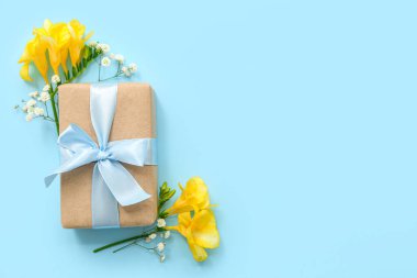 Şirin paketlenmiş hediye kutusu ve cyan arka planda çiçekler