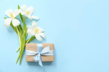 Güzel paketlenmiş hediye kutusu ve cyan arka planda çiçekler