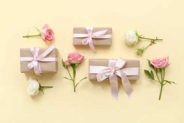 Zarif paketlenmiş hediye kutuları ve bej arka planda gül çiçekleri