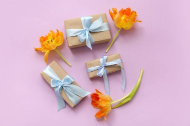 Şenlikli hediye kutuları ve pembe arka planda güzel çiçekler