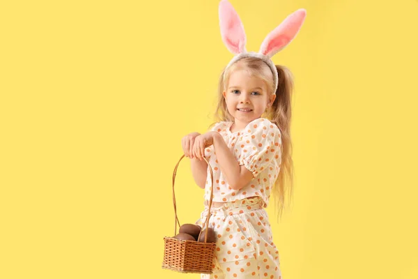 在兔子耳朵里可爱的小女孩 背景是黄色的巧克力复活节彩蛋 — 图库照片