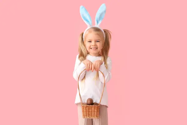 可爱的小女孩 长着一篮粉色背景的巧克力复活节彩蛋 — 图库照片