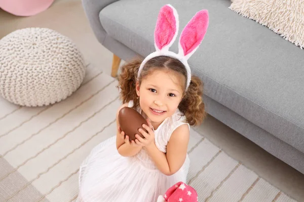 家里带着巧克力复活节彩蛋的兔子耳朵里可爱的小女孩 — 图库照片