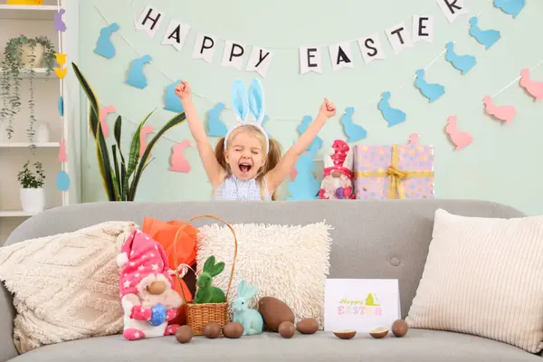 可爱的小女孩 长着小兔子耳朵 家里的沙发上挂着巧克力复活节彩蛋和玩具 — 图库照片