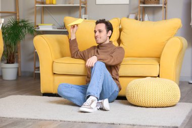 Genç adam eve kağıt uçak fırlatıyor.