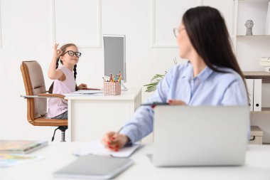 Annesi ofiste çalışırken resim çizen küçük kız.