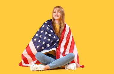 Sarı arka planda oturan Amerikan bayrağı taşıyan genç kız.