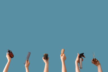 Mavi arka planda farklı kuaför malzemeleri olan bir sürü el.