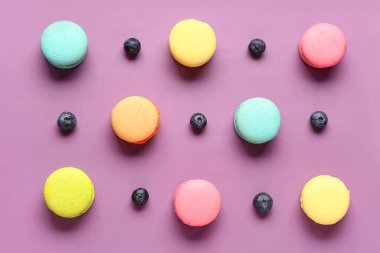 Mor arka planda farklı tatlı badem kurabiyeleri ve yabanmersinleri.