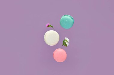 Uçan tatlı badem kurabiyeleri ve mor arka planda güzel çiçekler