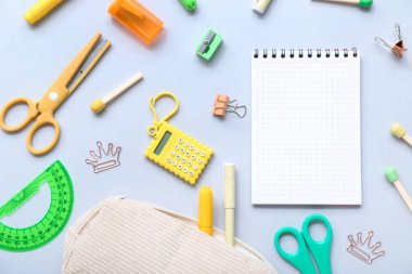 Mavi zemin üzerinde farklı kırtasiye malzemesi bulunan defter ve kalem çantası.