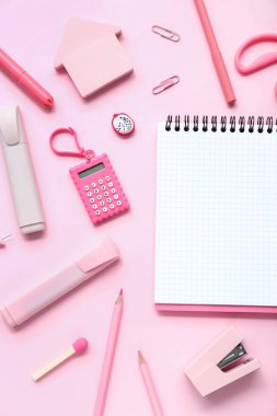 Pembe arka planda farklı kırtasiye malzemesi içeren defter.