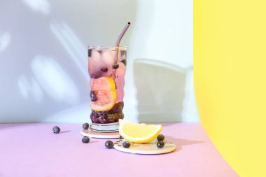 Renkli arka planda bir bardak taze yaban mersini limonatası.