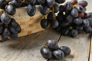 Gri ahşap arka planda tatlı siyah üzümlü hasır kase.