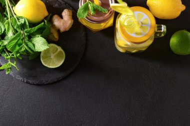 Mason kavanozları dolusu lezzetli limonata ve siyah masada limon.