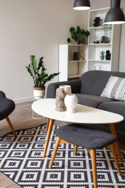 Gri kanepesi, sehpası ve parlak lambaları olan şık bir oturma odası.