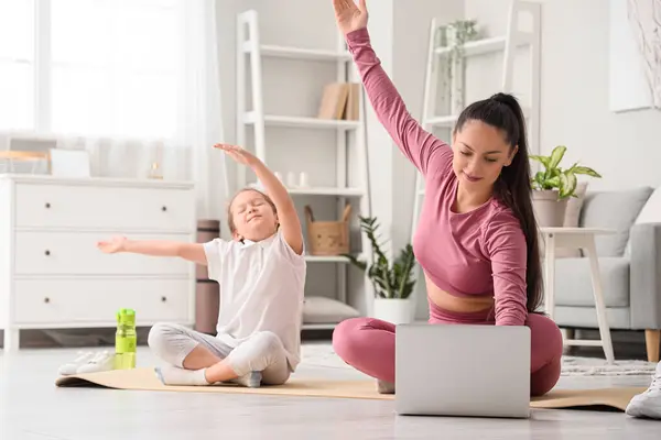 Working mother with her little daughter training at home