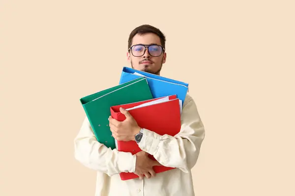 Young man with folders on beige background. Deadline concept