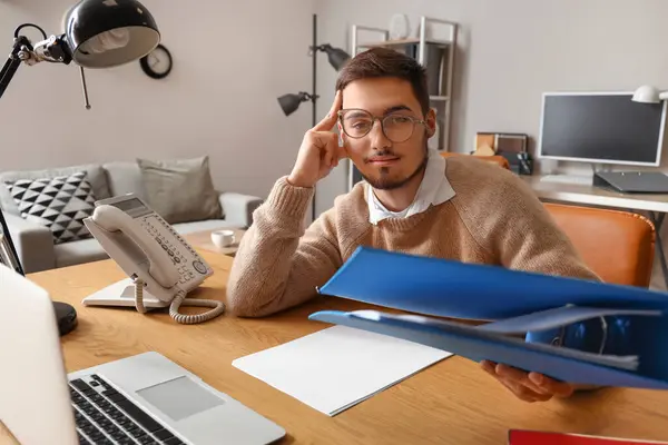 Stressed young man with folder working under deadline in office