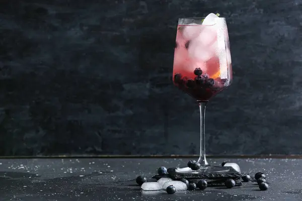 Glass of fresh blueberry lemonade on black background
