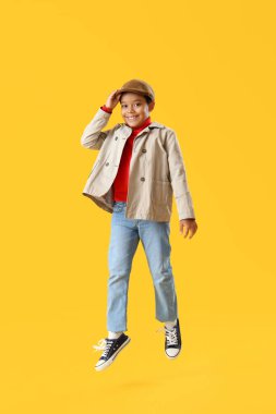 Sarı arka planda atlayan Afro-Amerikalı küçük çocuk.