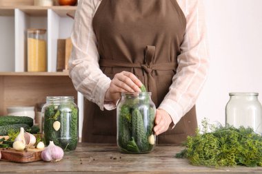 Mutfaktaki masada konserve için taze salatalık hazırlayan kadın.