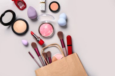 Gri arka planda makyaj malzemesi olan alışveriş torbası.