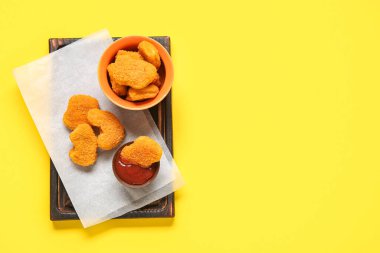 Sarı arka planda lezzetli nuggetlar ve ketçaplı kase.