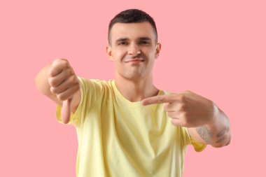 Pembe arka planda hoşlanmadığını gösteren genç bir adam.