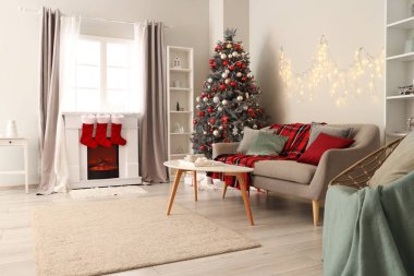 Oturma odasının içinde kanepe, Noel ağacı ve şömine var.