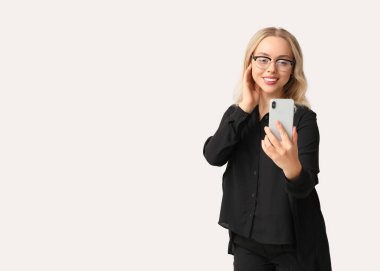 Güzel genç iş kadını beyaz arka planda selfie modern akıllı telefon kullanıyor.